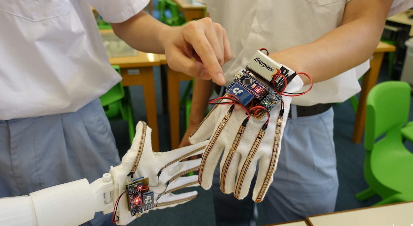 Sensor glove prototype held beside a printed robotic hand